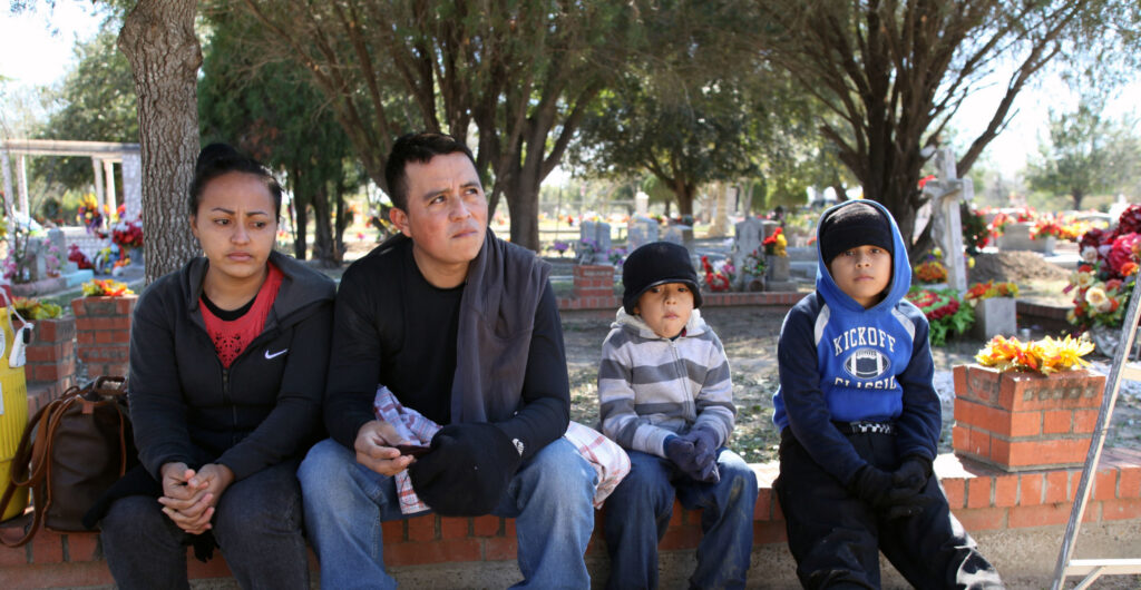 A family from El Salvador waits to be taken into custody at the city cemetery after being detained by the Border Patrol for illegally entering the United States by crossing the Rio Grande River.