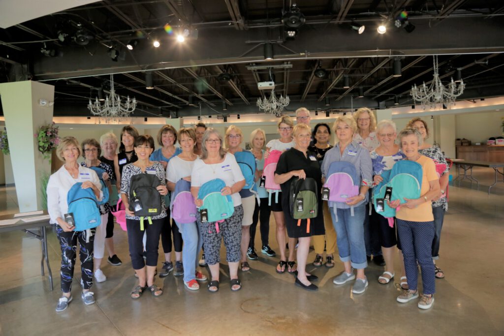 Group of people smiling and holding backpacks.