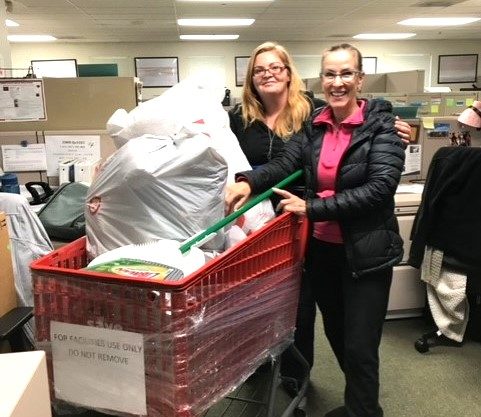 Two people smiling with shopping cart full of donated goods.