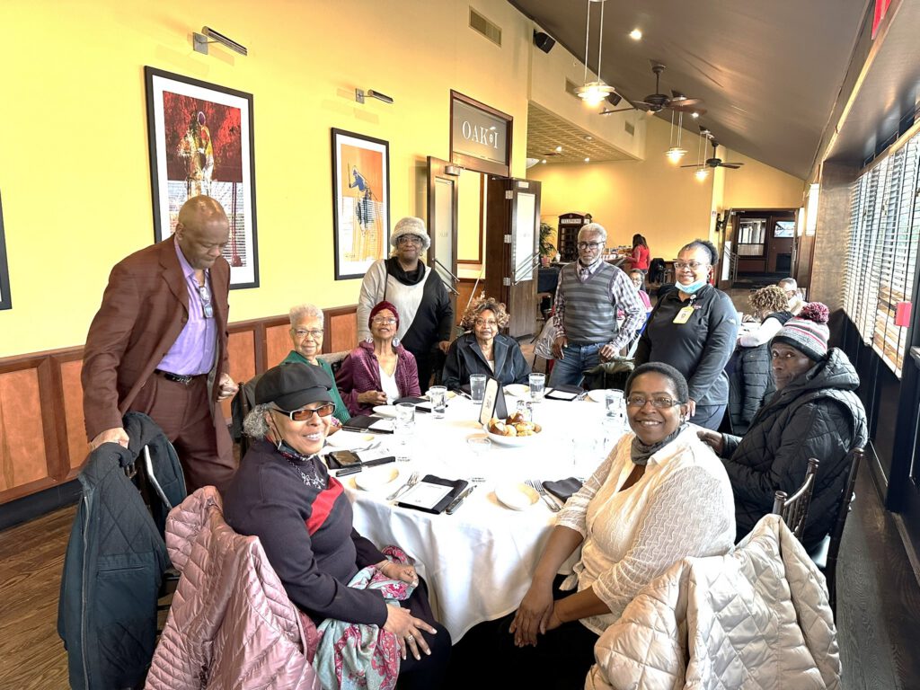 Group of people around a restaurant round table and smiling at the camera.